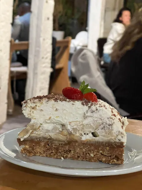 Une haute part de banoffee pie garnie de crème, de copeaux de chocolat et de fraises