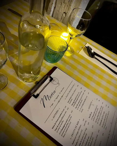 La carte sur un porte-bloc à côté d’une carafe d’eau et d’une bougie sur une nappe vichy